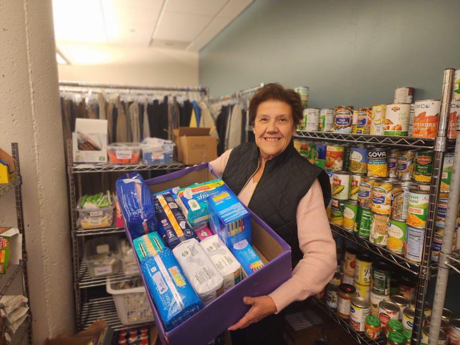 Jamie Cochran, Womens HERstory Month committee member, inside the Falcon Community Outreach Center, holding a collection bin of supplies from the Feminine Hygiene product drive.